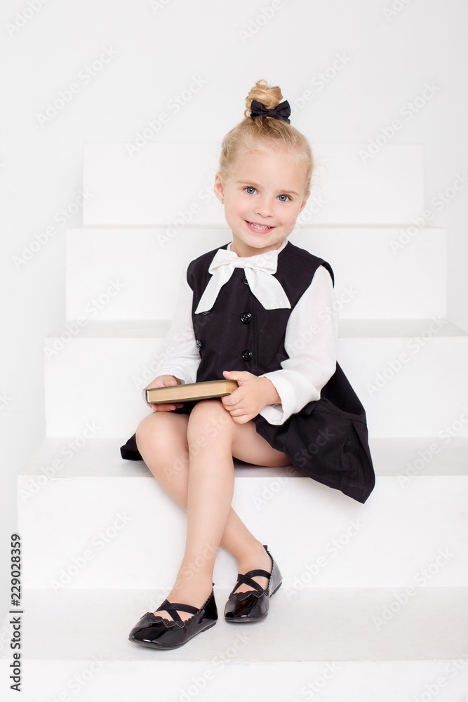 Kid model, girl in a school uniform, girl sitting on a stairs foto de Stock  | Adobe Stock
