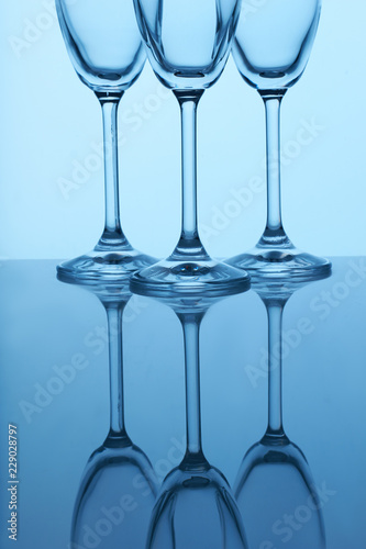 Long stem champagne flutes. Reflective surface, blue lighting.