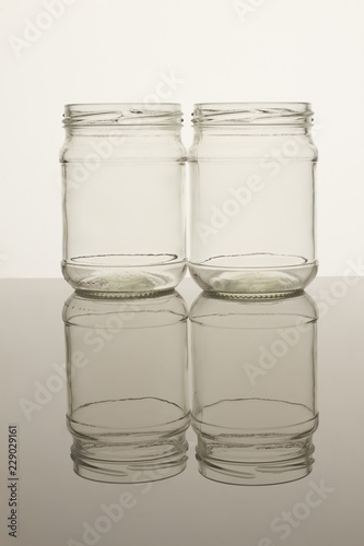 Set of two jars isolated on white background. Reflective surface.