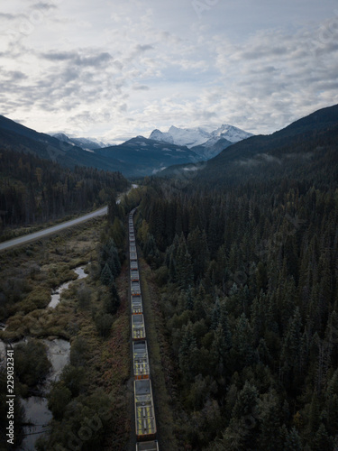 Aerial drone shot of Canadian country side with road, rail and creek with mountains in background