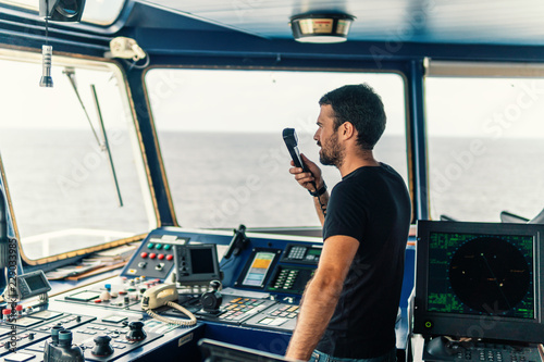 Marine navigational officer is reporting by VHF radio during navigation watch. Bridge GMDSS watch photo