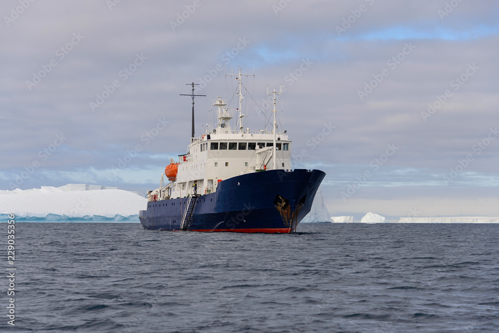 Fototapeta premium Expedition ship with iceberg in Antarctic sea