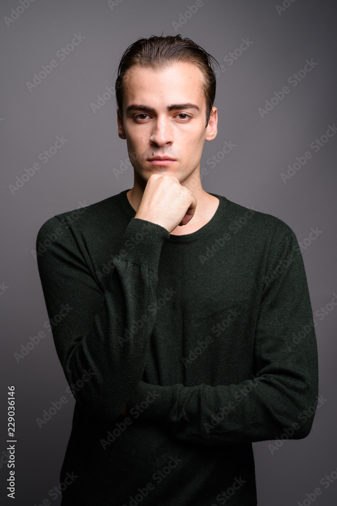 Young handsome man wearing green long sleeved shirt and thinking Young handsome man wearing green long sleeved shirt and thinking