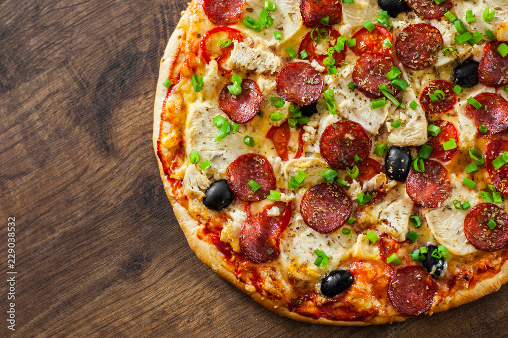 Pizza with Chicken meat, Mozzarella cheese, pepperoni, tomato, olive, salami. Italian pizza on wooden background