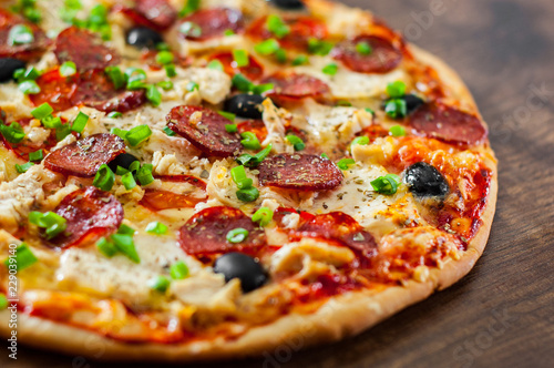 Pizza with Chicken meat, Mozzarella cheese, pepperoni, tomato, olive, salami. Italian pizza on wooden background