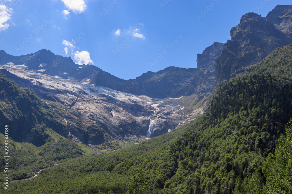 Closeup view mountains scenes and far away waterfall in national park Dombai, Caucasus, Russia, Europe. Summer landscape, sunshine weather and sunny day