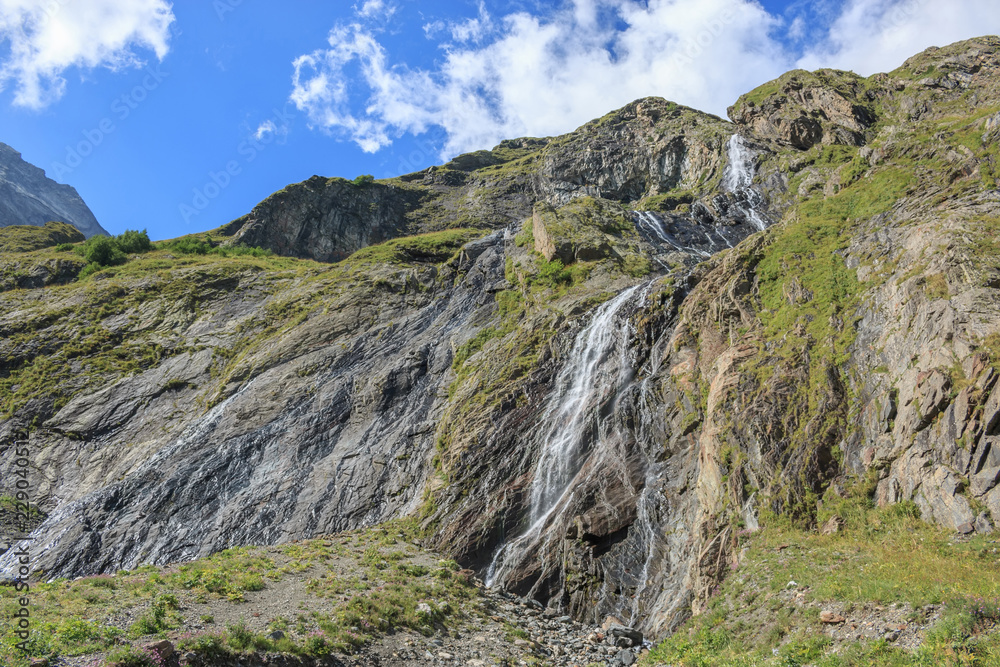 Closeup view waterfall scenes in mountains, national park Dombai, Caucasus, Russia, Europe. Summer landscape, sunshine weather, dramatic blue sky and sunny day