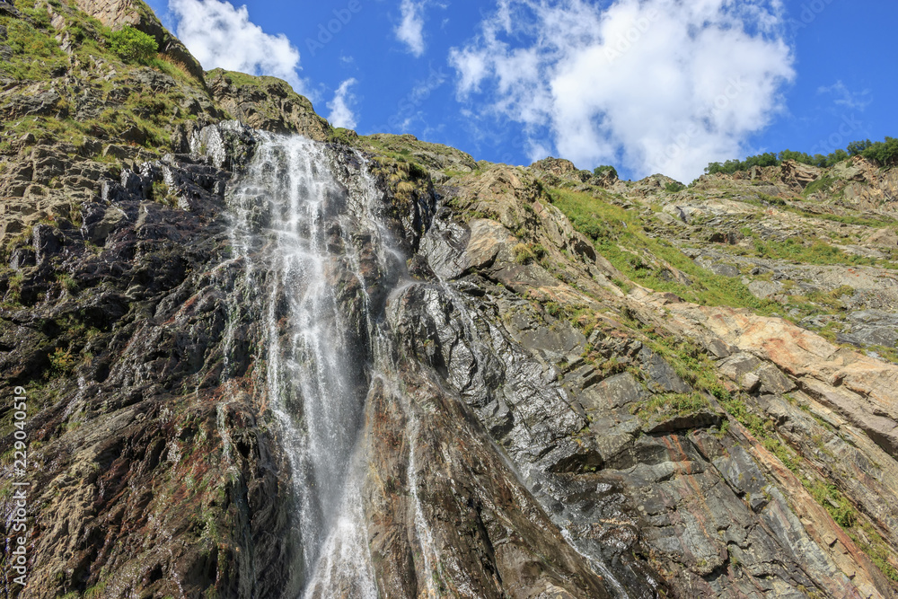 Closeup view waterfall scenes in mountains, national park Dombai, Caucasus, Russia, Europe. Summer landscape, sunshine weather, dramatic blue sky and sunny day