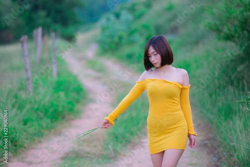 Portrait of beautiful asian woman wear yellow dress at the field,Thailand people