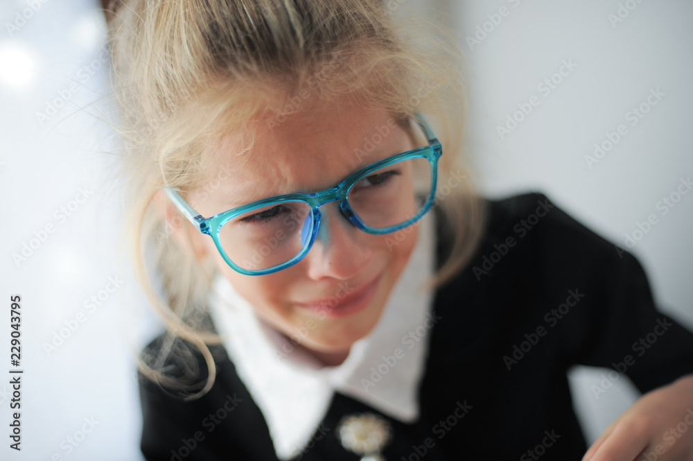 little girl in blue glasses and school black and white dress crying bitterly little girl in blue glasses and school black and white dress crying bitterly