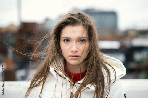 Portrait of blond young woman with blue eyes standing outdoors