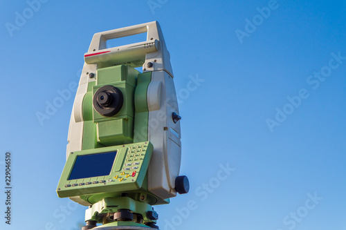 Surveyor equipment (theodolit or total positioning station) on the construction site of the motorway or road with blue sky in background