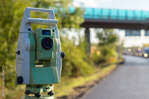 Surveyor equipment (theodolit or total positioning station) on the construction site of the motorway or road with bridge in background