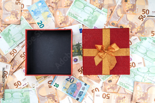 An open red gift on a banknote background. Top view © Kindarts