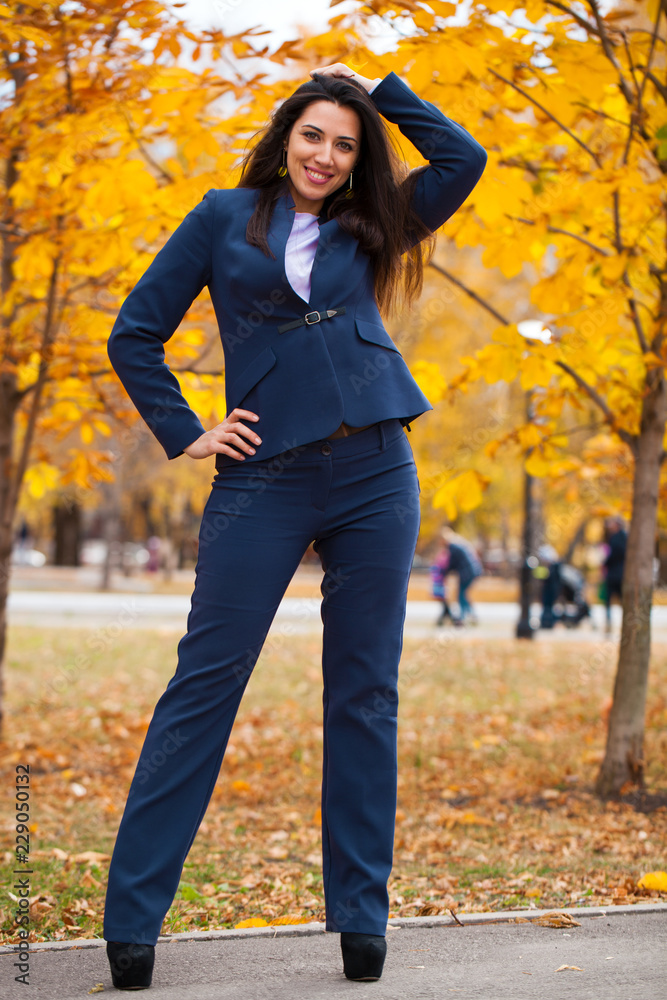 Happy arab businesswoman in blue suit walking in autumn park