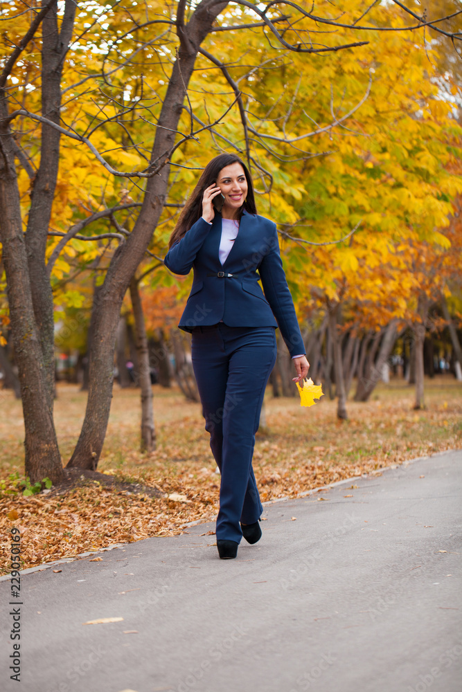 Happy arab businesswoman in blue suit walking in autumn park
