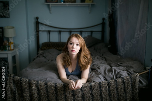 Portrait of blond young woman lying on bed at home
