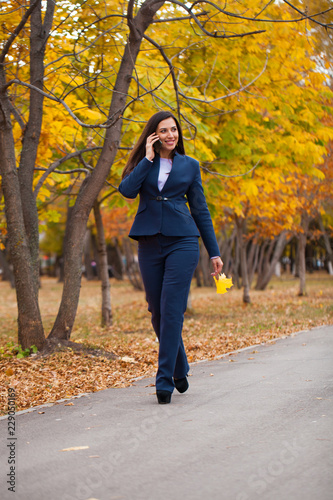 Happy arab businesswoman in blue suit walking in autumn park © Andrey_Arkusha