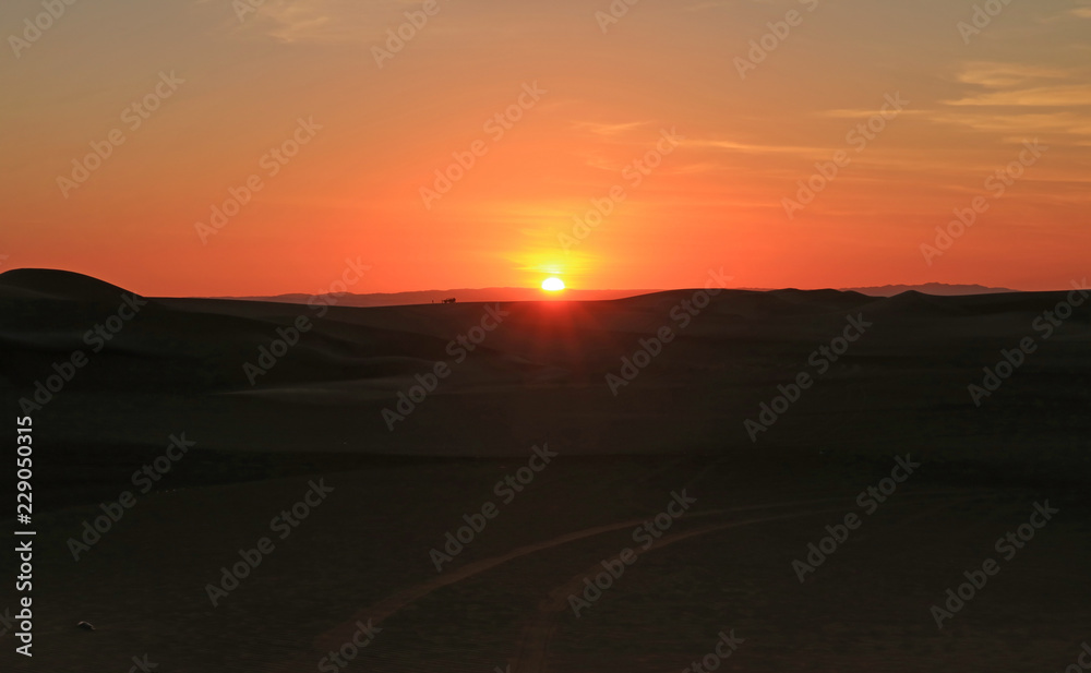 Obraz premium Stunning sunset over the sand dune of Huacachina desert with people and dune buggy in distance, Ica region, Peru