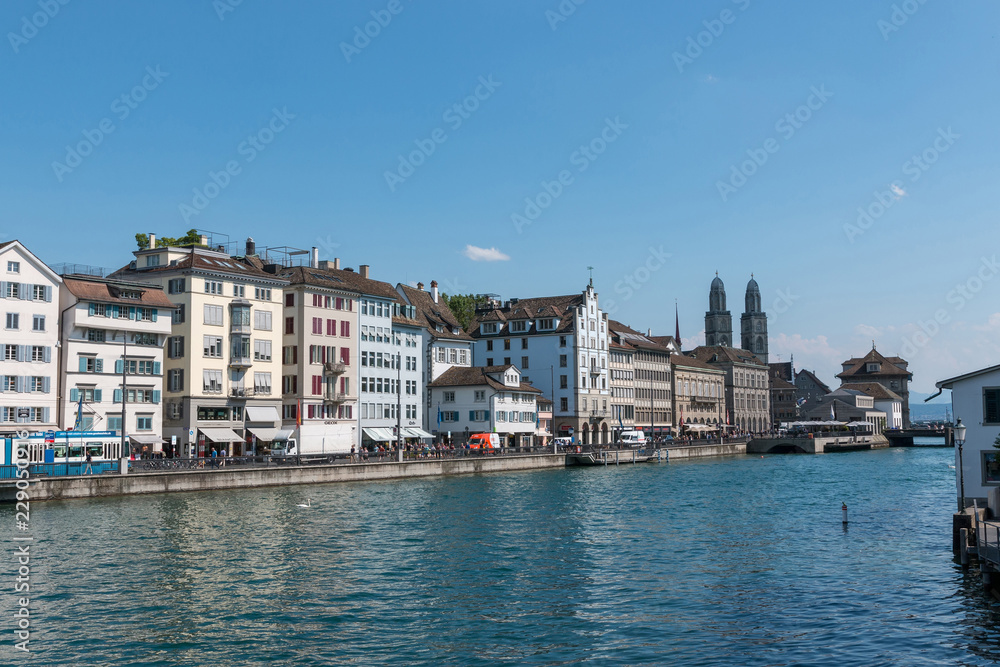 Zurich, Switzerland - June 19, 2017: Panoramic view of historic Zurich city center with famous Grossmunster Church and river Limmat. Summer day with blue sky