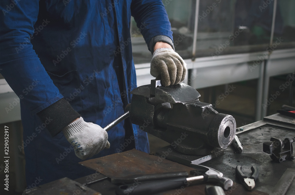 Man worker is working with iron detail on vise grip on blacksmith table. Man worker is working with iron detail on vise grip on blacksmith table.