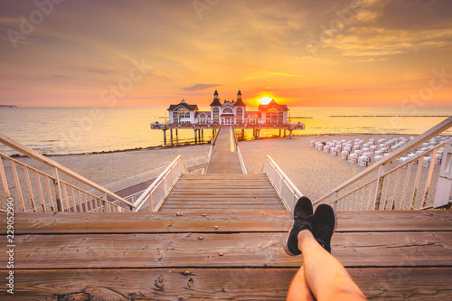 Young man sitting on wooden pier enjoying sunrise at Seebrucke Sellin, Baltic Sea, Germany photo