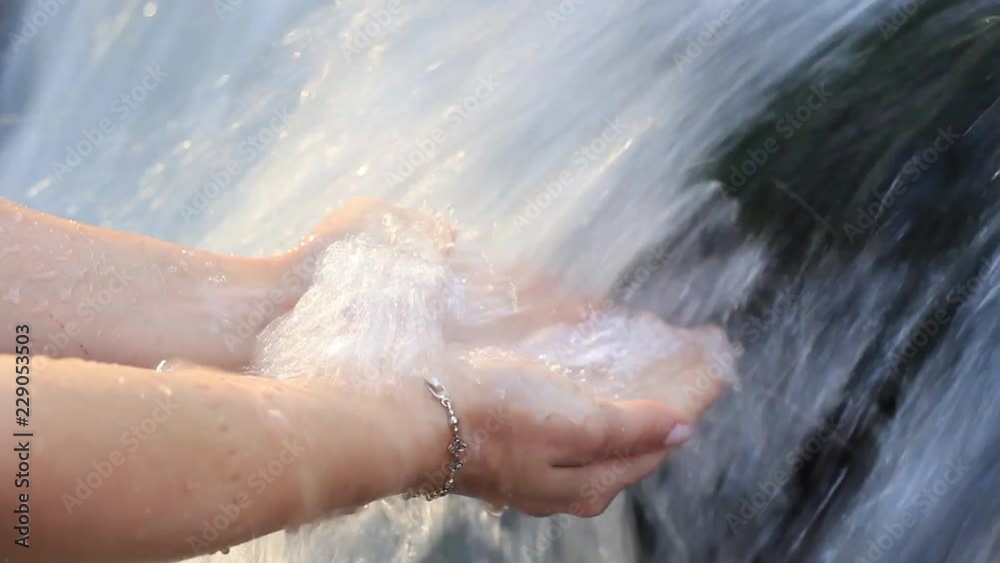 women's hands in the clear water of the waterfall women's hands in the clear water of the waterfall