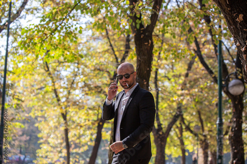 A handsome young businessman talking on his phone in the park