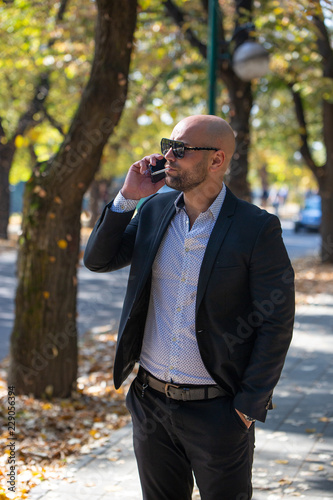 A handsome young businessman talking on his phone in the park