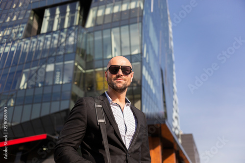 Handsome elegant businessman with sunglasses in front of office building