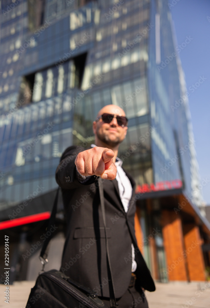 Handsome elegant businessman with sunglasses in front of office building