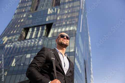 Handsome elegant businessman with sunglasses in front of office building
