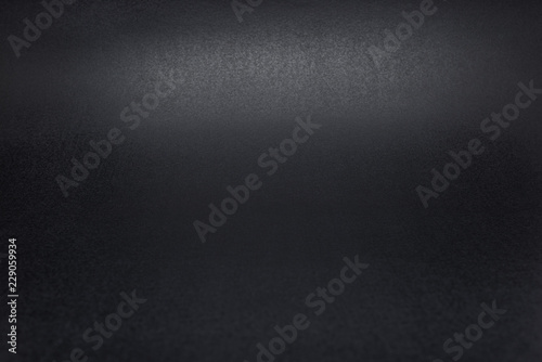 Black, rough textured background lit with dim light.