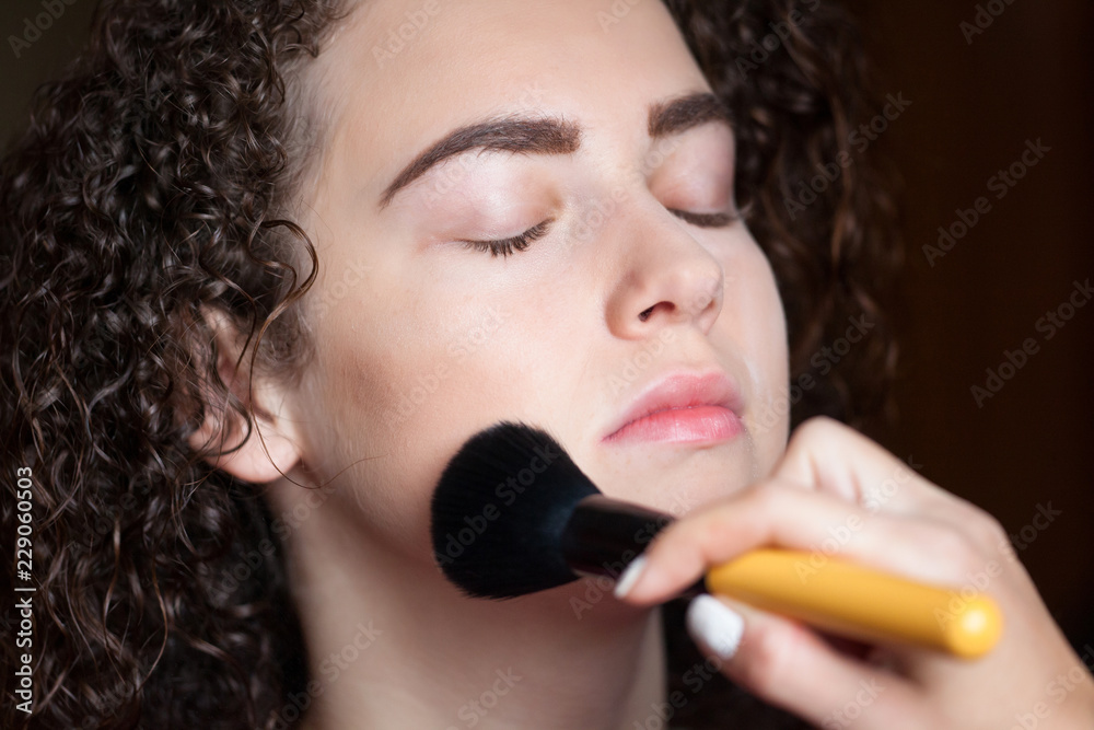 Closeup portrait of beautiful woman getting professional make-up with brush. Beauty and makeup concept Closeup portrait of beautiful woman getting professional make-up with brush. Beauty and makeup concept