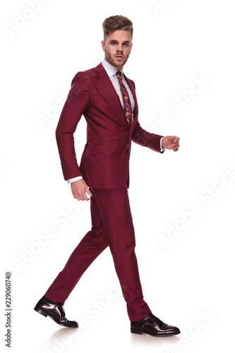 side view of young businessman with parted lips walking photo