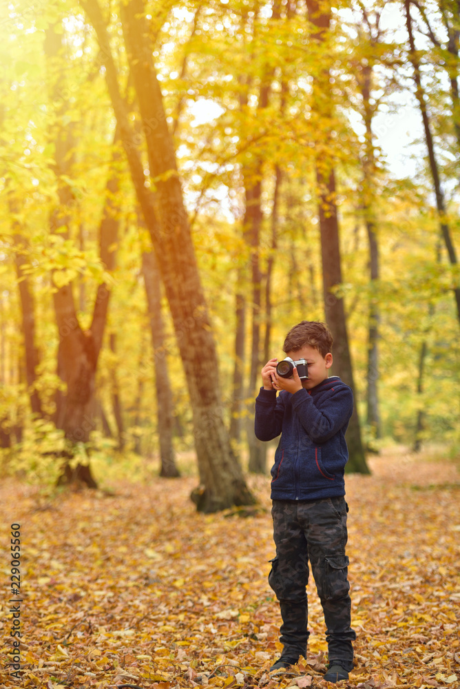 Creative child, kid photographer (a little boy) with a camera taking pictures of colorful autumn forest Creative child, kid photographer (a little boy) with a camera taking pictures of colorful autumn forest