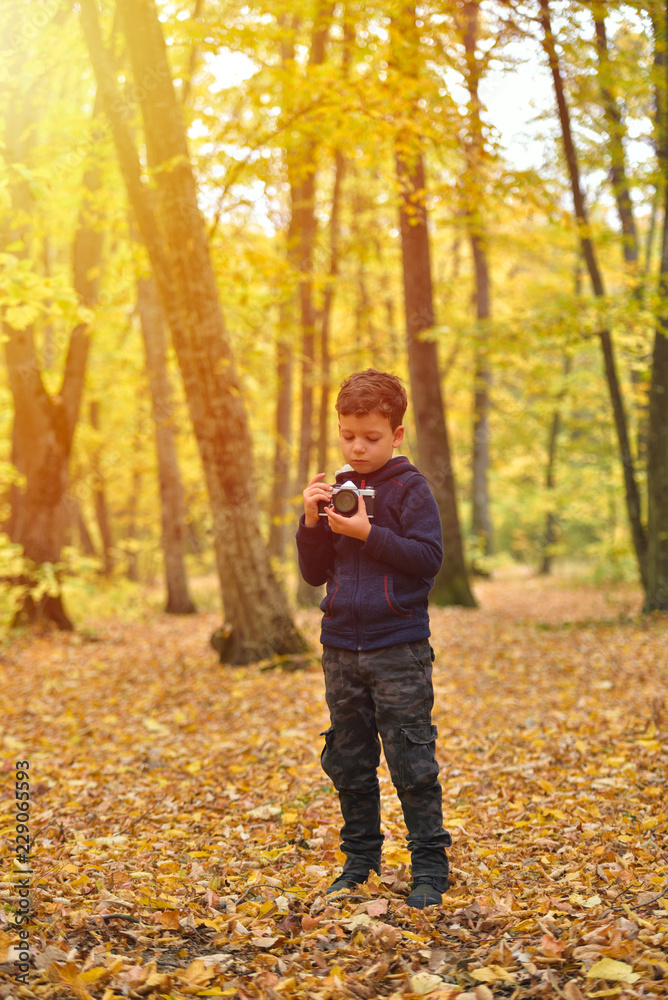 Creative child, kid photographer (a little boy) with a camera taking pictures of colorful autumn forest Creative child, kid photographer (a little boy) with a camera taking pictures of colorful autumn forest