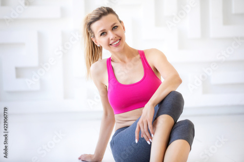 Close up portrait of attractive fit woman sitting on the floor in gym.