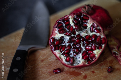 Juicy pomegranate on a cutting board on dark background photo