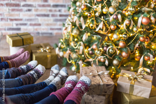 Close-up of legs in socks near Christmas tree with gift boxes