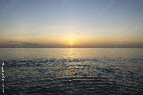 Calming and beautiful orange sunset against blue seashore