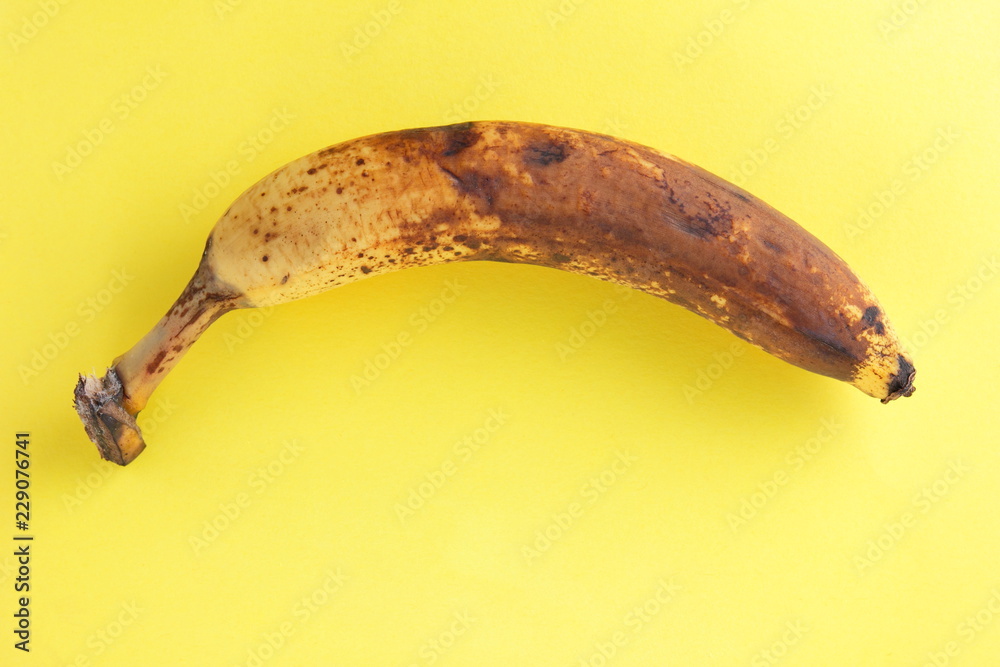 Blackened banana. Banana on yellow background. Spoiled tropical fruit