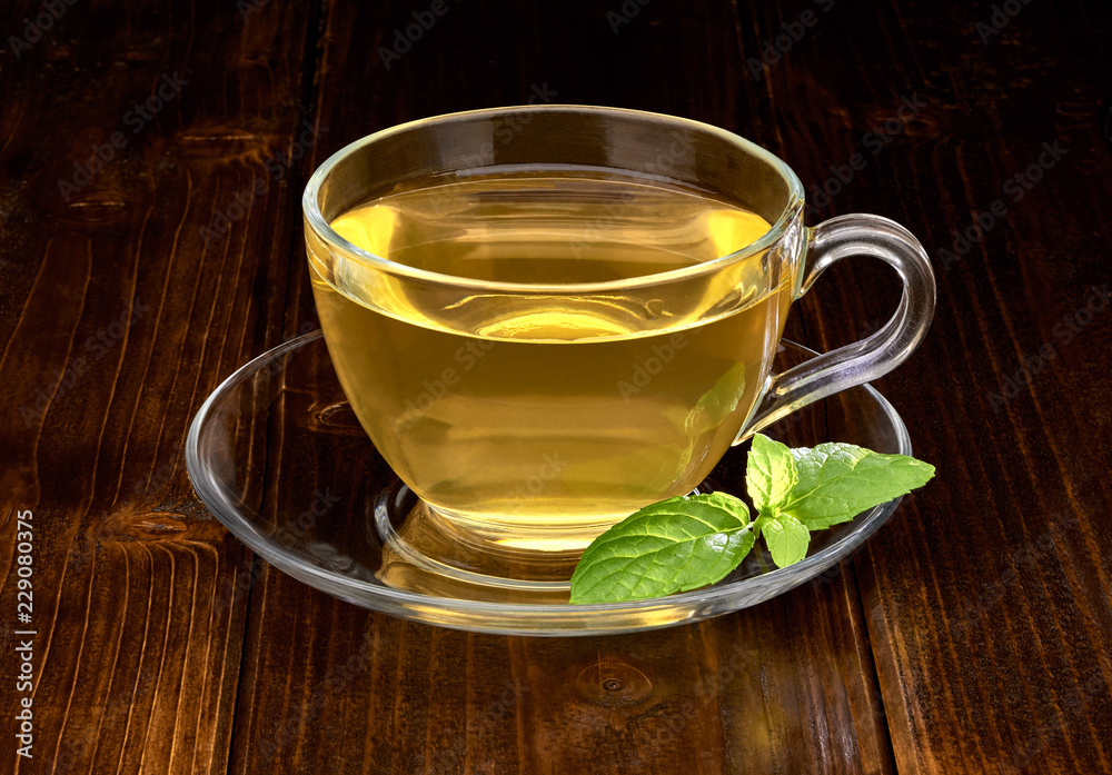 Green tea in cup with leaves on wooden table background Green tea in cup with leaves on wooden table background