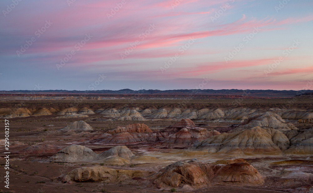 Rainbow Hills in China. Rainbow City, Wucai Cheng. Colorful layered landforms in a remote desert area of Fuyun County. Uygur Autonomous Region, Xinjiang Province. Sunrise - Pink, Purple and Blue Sky