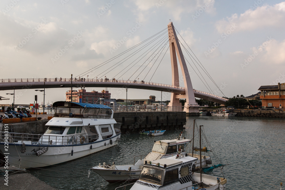 View from Fisherman's Wharf located along the coast of Tamsui District, New Taipei City Taiwan. Harbor with boats and sunset with calm water, ocean boats and buildings in the background. View from Fisherman's Wharf located along the coast of Tamsui District, New Taipei City Taiwan. Harbor with boats and sunset with calm water, ocean boats and buildings in the background.