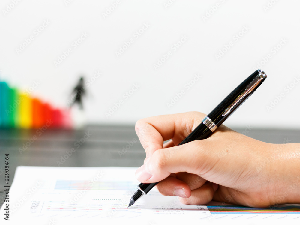 business graph chart and hand holding pen on table. business graph chart and hand holding pen on table.