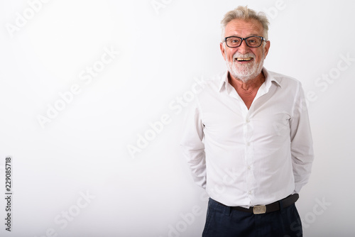 Studio shot of happy senior bearded man smiling with hands behin photo