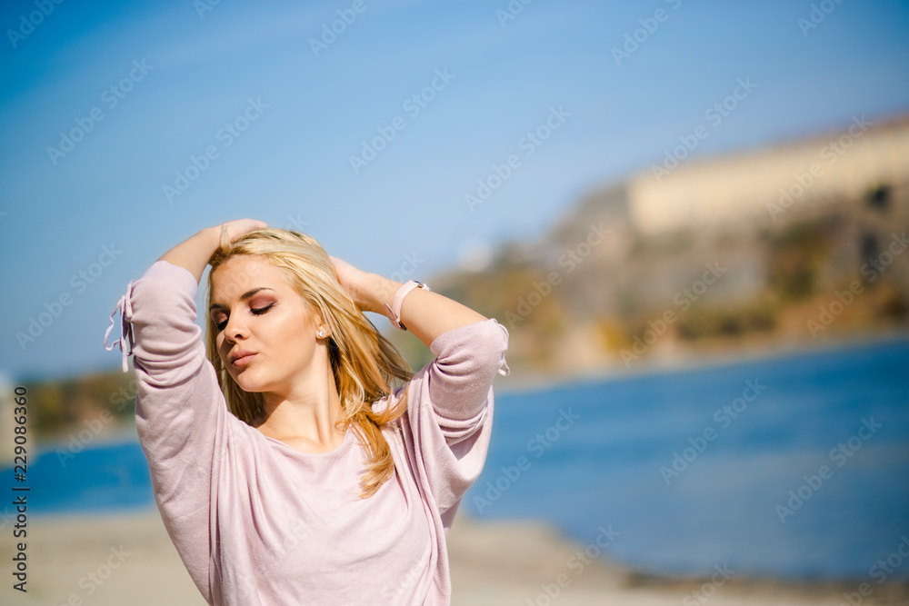 Photographing a girl during autumn on a beach near a river with a blurred background