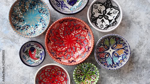 Collection of empty moroccan colorful decorative ceramic bowls. Composition captured from top view, flat lay. Placed on grey stone background.