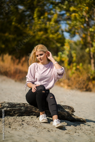 Photographing a girl during autumn on a beach near a river with a blurred background